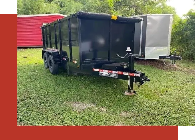 A black trailer is parked in the grass.