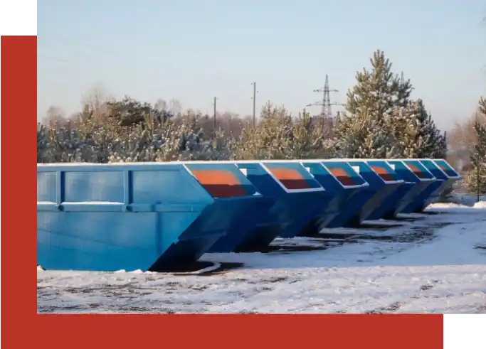 A row of blue and orange dumpster trucks in the snow.